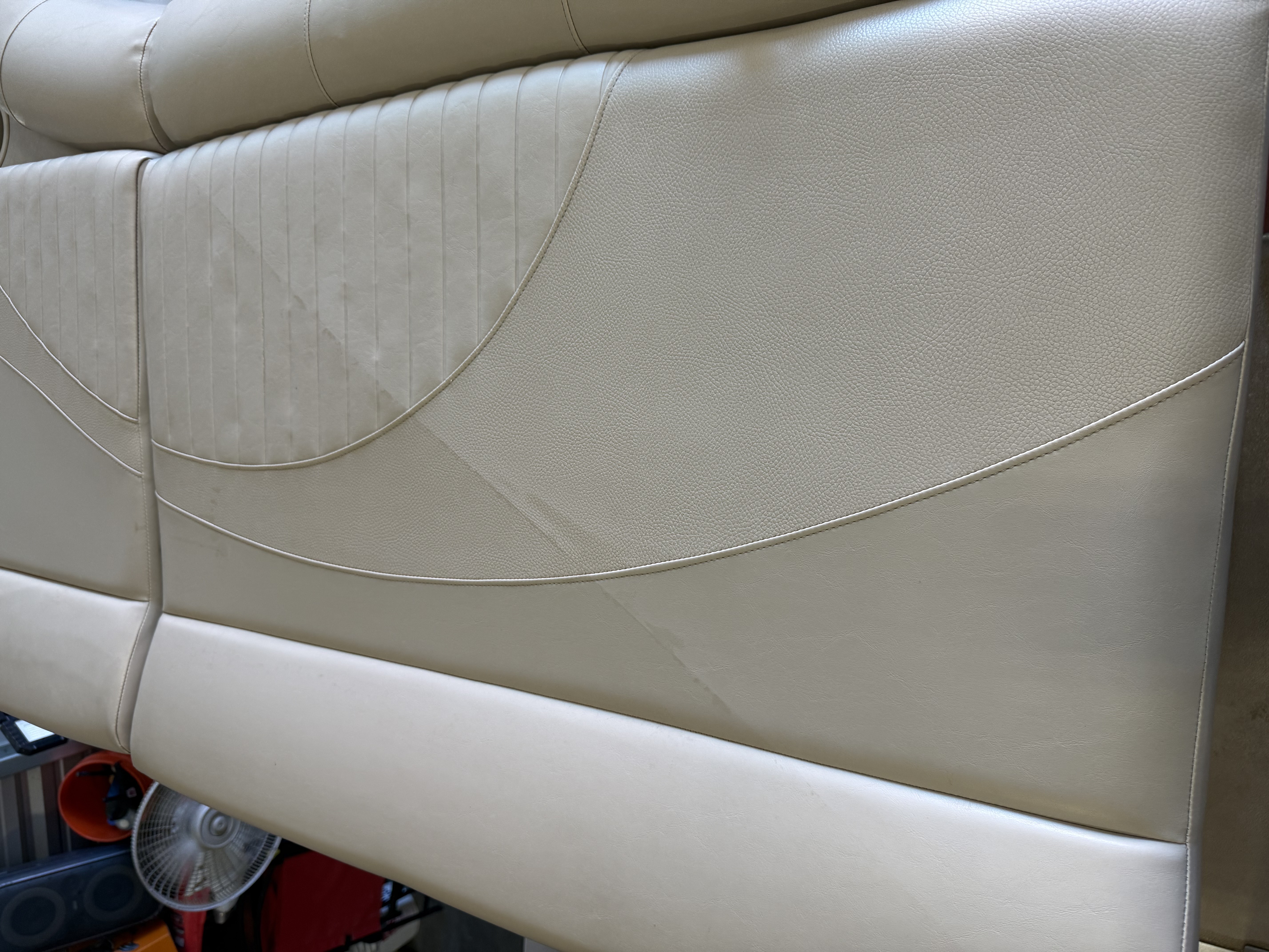 Close-up of cream-colored leather boat seat with curved stitching and cushioned sections