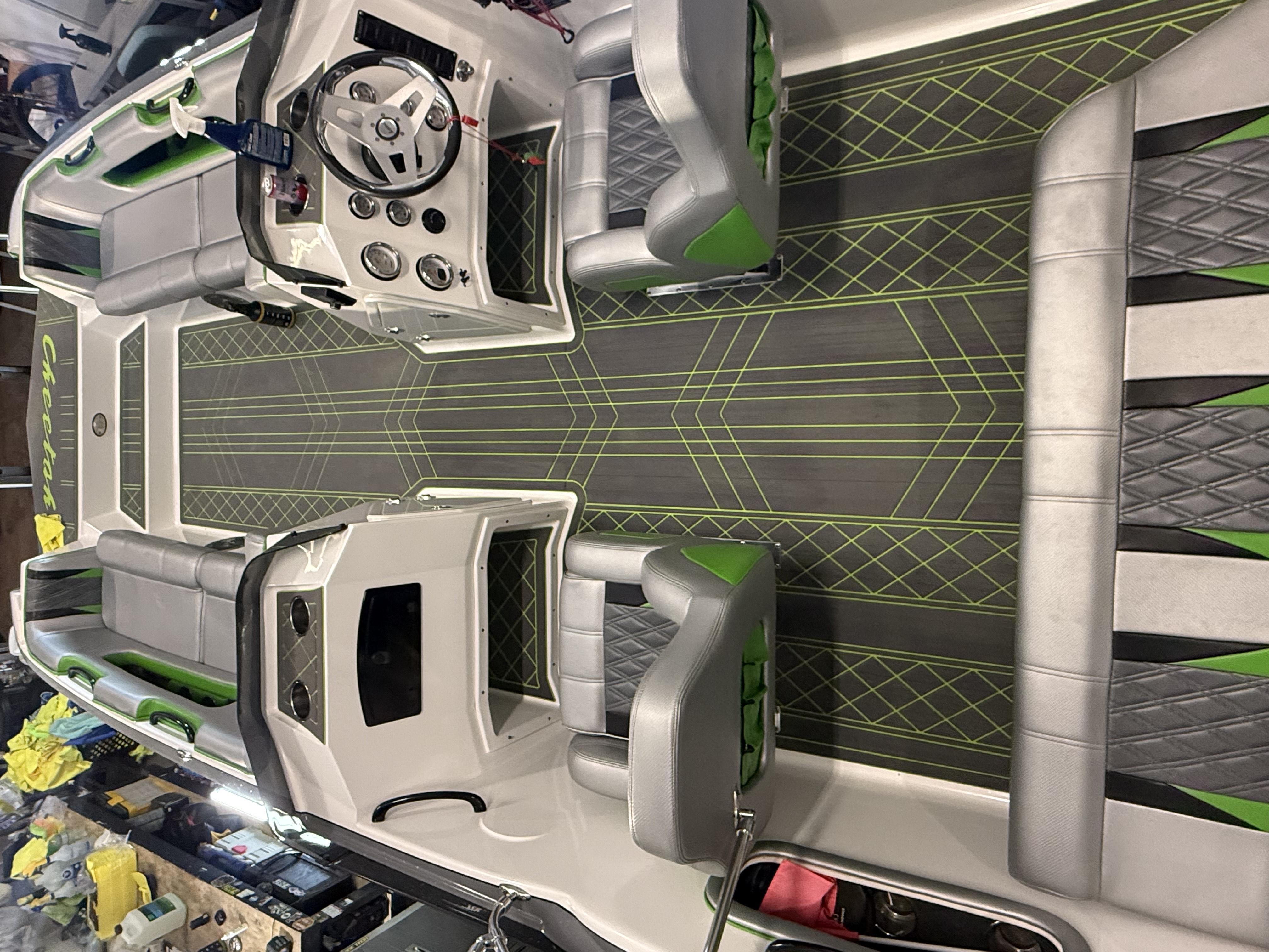 Two white and green jet skis with steering wheels displayed at a boat show