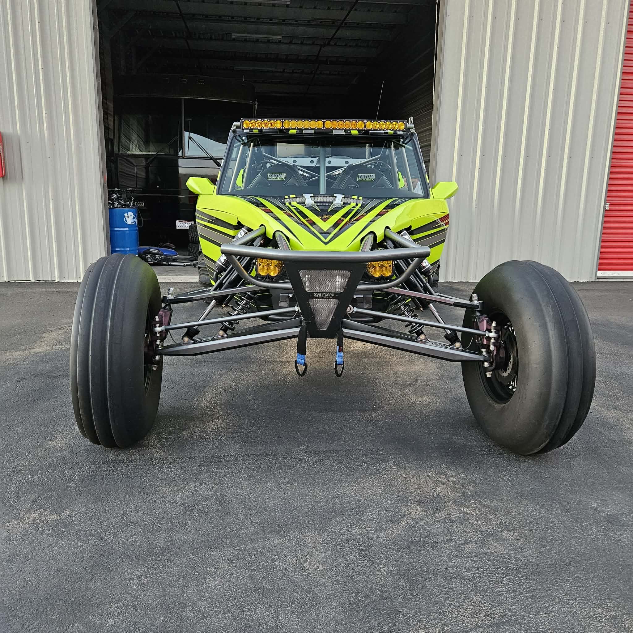 Bright yellow and black dune buggy with large tires parked in warehouse