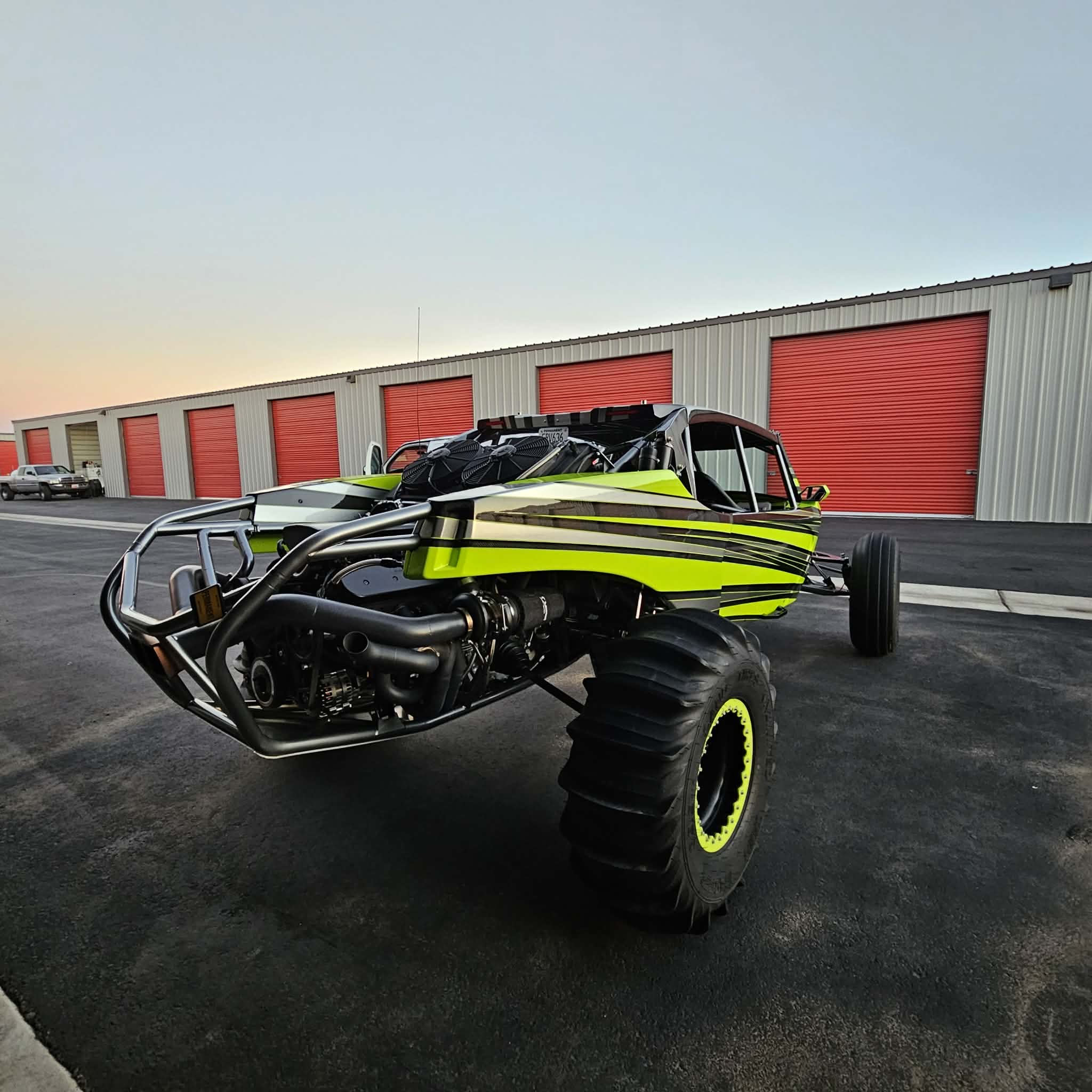 Custom neon green and black off-road buggy with open doors outside storage units.