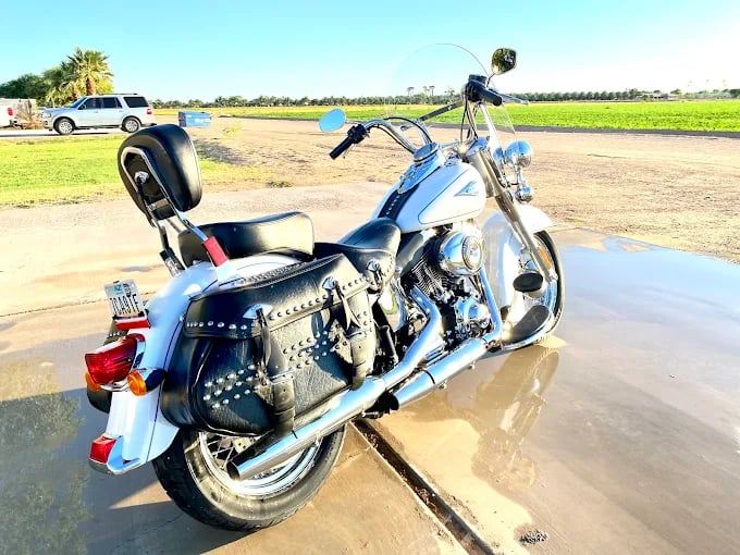 Blue and white cruiser motorcycle parked in shallow water with truck visible behind