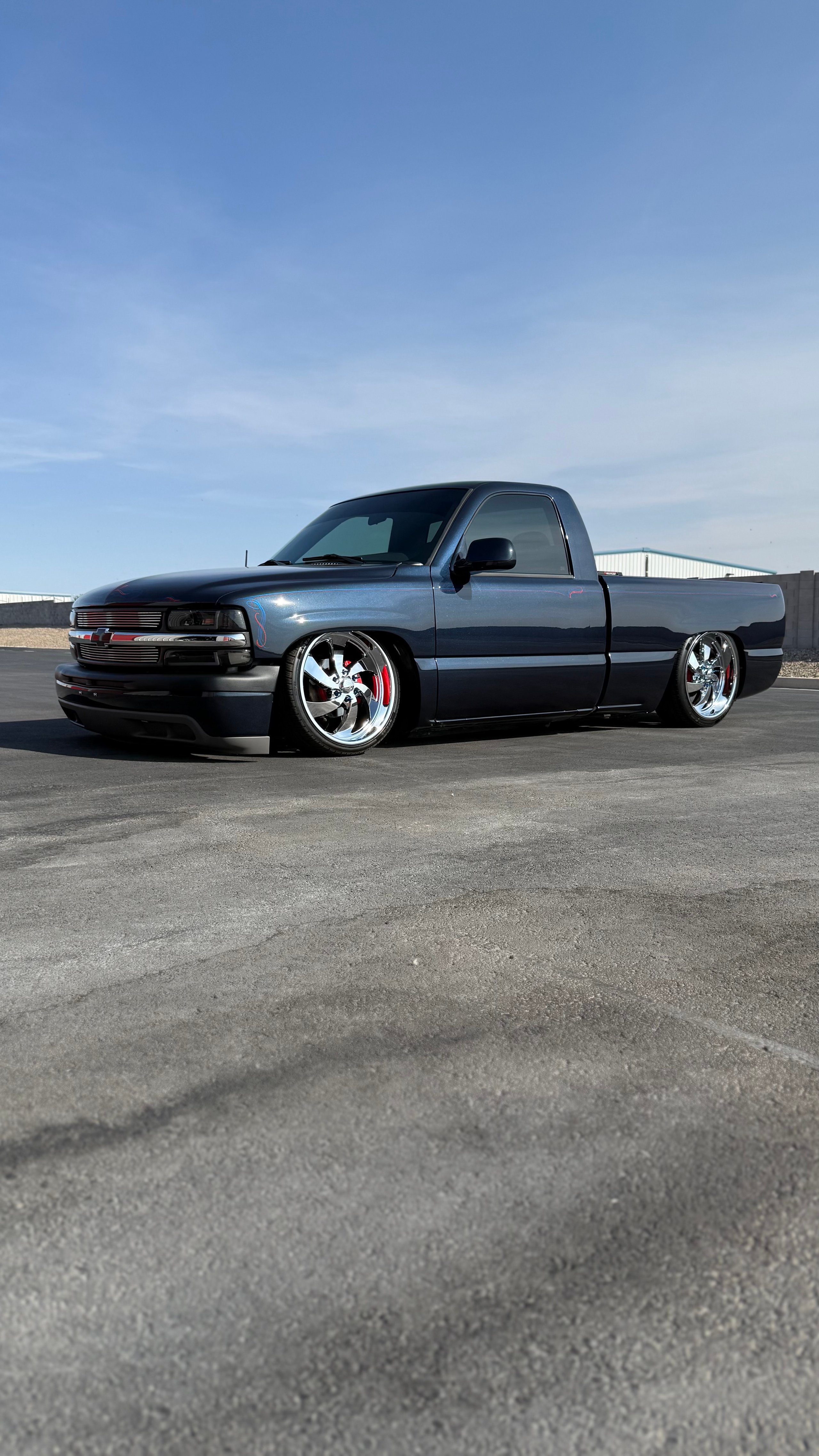Custom black lowered pickup truck with chrome wheels parked on asphalt